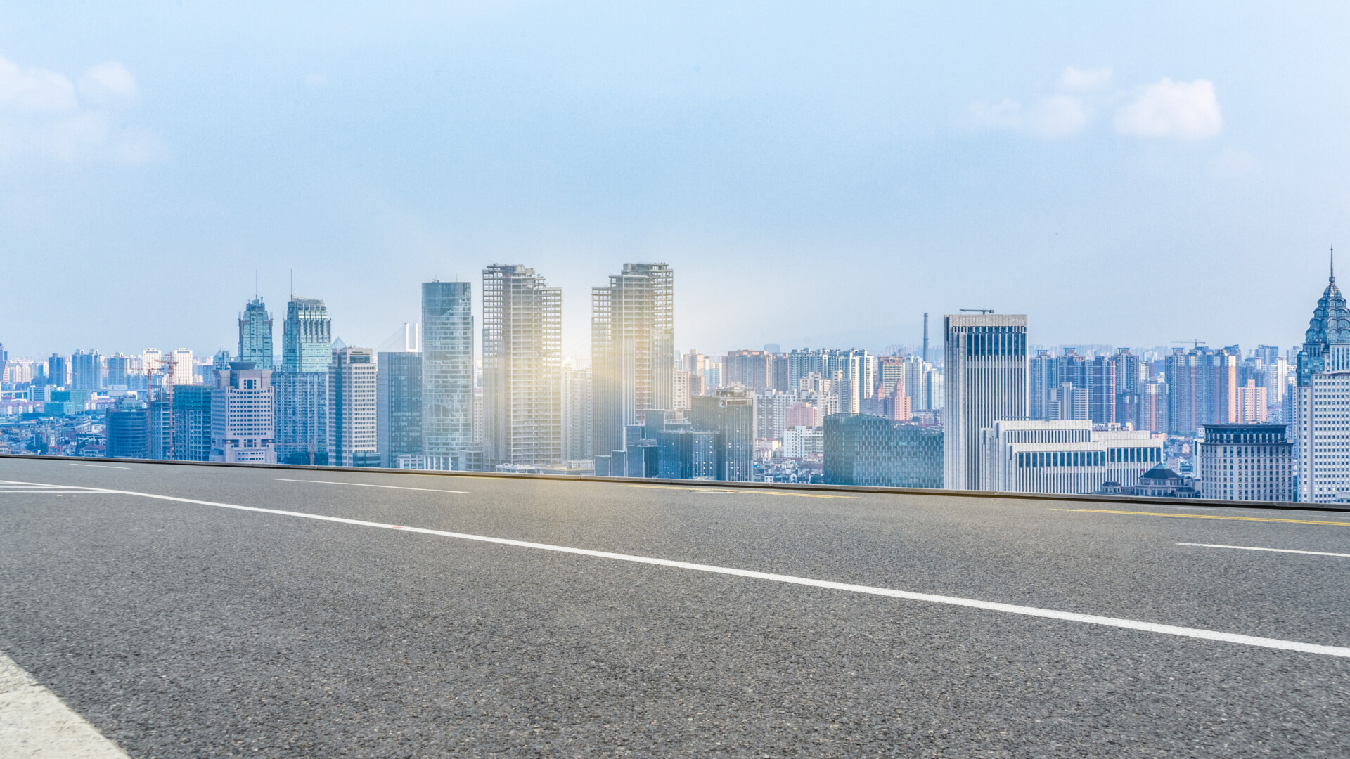 empty-road-leading-to-modern-city-skyline-under-blue-sky